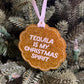 A scalloped glitter ornament in metallic copper-orange with white text reading 'TEQUILA IS MY CHRISTMAS SPIRIT,' hanging from a pale pink ribbon on a green Christmas tree.